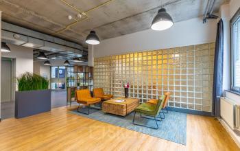 Furnished office space for rent in Hilversum at Mozartlaan 25, featuring a modern seating area with colorful chairs and a coffee table on a wooden floor, ideal for relaxed meetings.