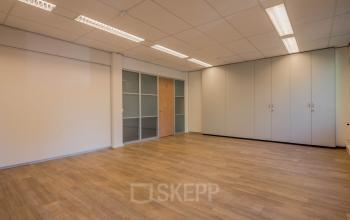 Unfurnished office space with wooden flooring and built-in cabinets at Mozartlaan 25, Hilversum, ideal for office space rental.
