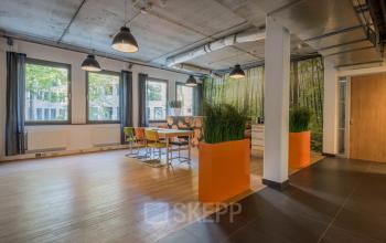 Modern office space for rent at Mozartlaan 25, Hilversum, featuring bright natural lighting, stylish furnishings, and a collaborative workspace environment with a nature-inspired decor.
