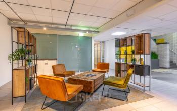 Hilversum office space rental featuring a furnished lobby with colorful chairs and bookshelves at Mozartlaan 25.