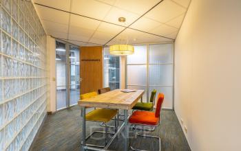 Cozy furnished office space to rent at Mozartlaan 25, Hilversum, featuring a wooden table and colorful chairs, ideal for small meetings.
