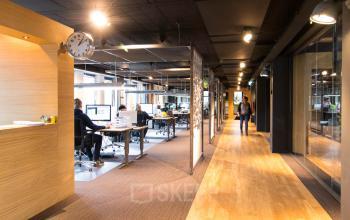 A modern office space with people working at desks, located at Franciscusweg 219, Hilversum. Ideal for office space rental, it offers a productive work environment.