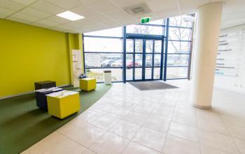 Bright entrance area at Franciscusweg 219 in Hilversum, ideal for office space rental, featuring colorful seating and large windows for natural light.
