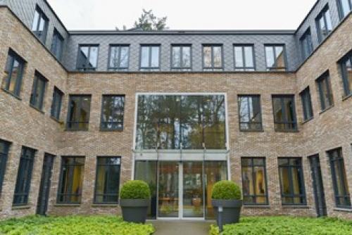 Exterior view of the office building at Catharina van Renneslaan 20 in Hilversum, showcasing a brick facade with large windows and greenery in the front.