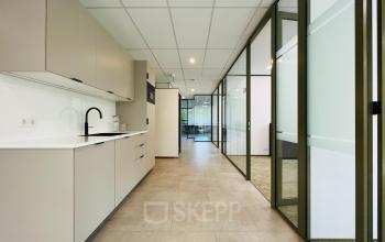 Modern office space rental at Marathon 2, Hilversum, featuring a sleek interior with glass partitions and cabinetry.
