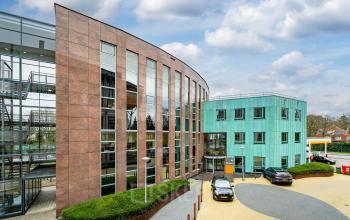 Modern office building exterior at Olympia 4, Hilversum, featuring contemporary design and ample parking spaces. Ideal for office space rental, with easy access for professionals.