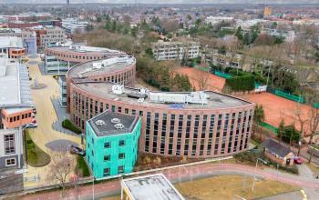 Exterior view of office building at Olympia 4, Hilversum. Modern architecture with distinctive wavy design, set in a business district. Ideal for office space rental.