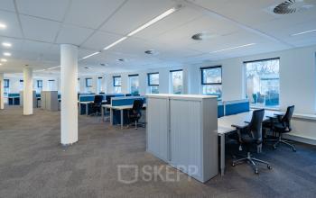 Spacious open-plan office at Olympia 4, Hilversum, ideal for businesses seeking office space rental. Features multiple workstations with ergonomic chairs and ample natural light through large windows.