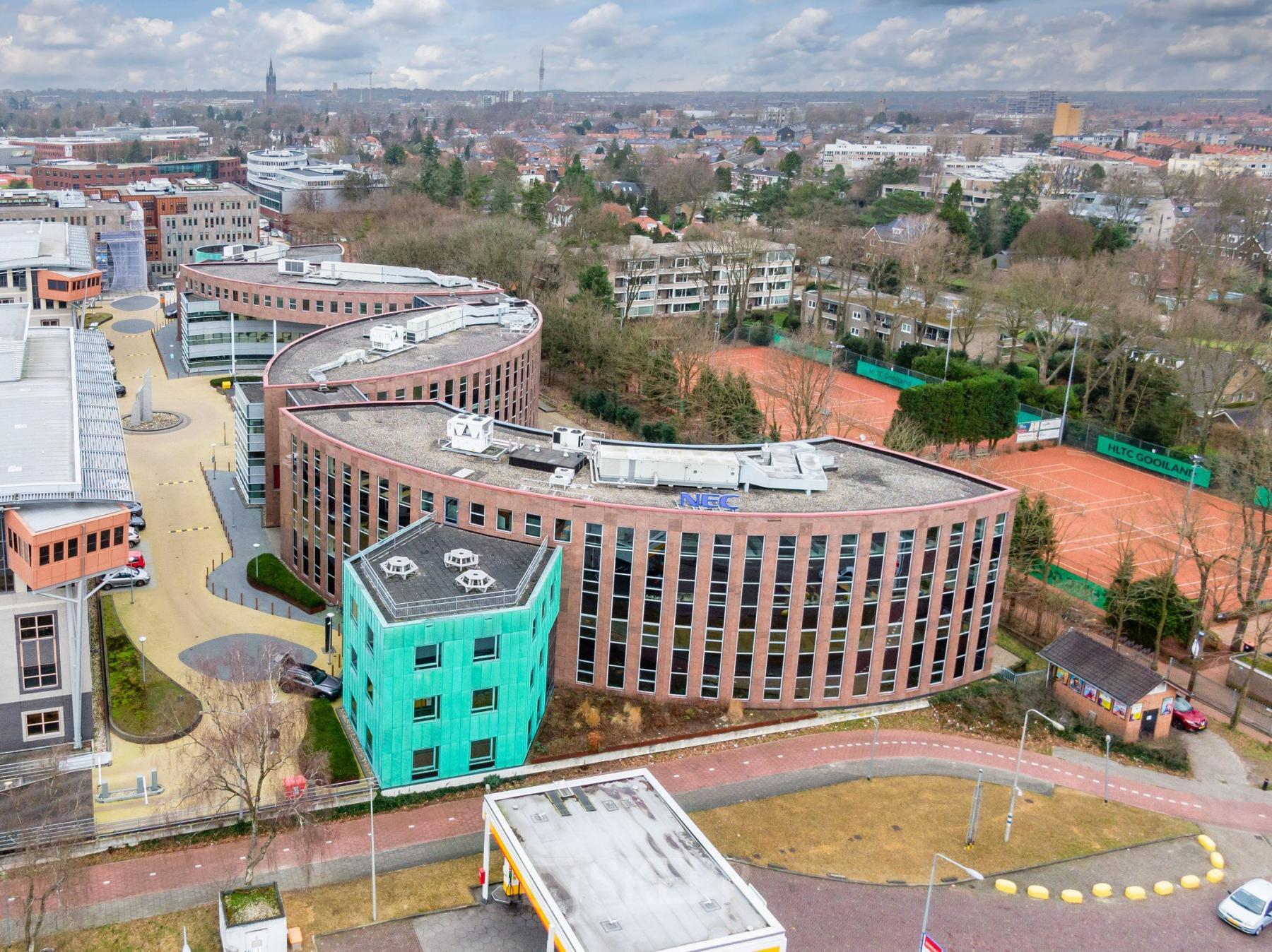 Exterior view of office building at Olympia 4, Hilversum. Modern architecture with distinctive wavy design, set in a business district. Ideal for office space rental.