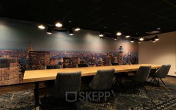 Modern conference room at Steijnlaan 16, Hilversum, featuring a large wooden table and cityscape wall mural, ideal for office space rental.