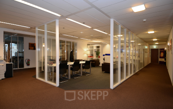 Modern office space rental at Olympia 2D in Hilversum featuring glass partition walls and well-equipped workstations.