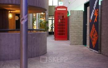Stylish office interior featuring a red phone booth and unique architectural elements at Catharina van Renneslaan 8-10, ideal for those looking to rent office space in Hilversum.