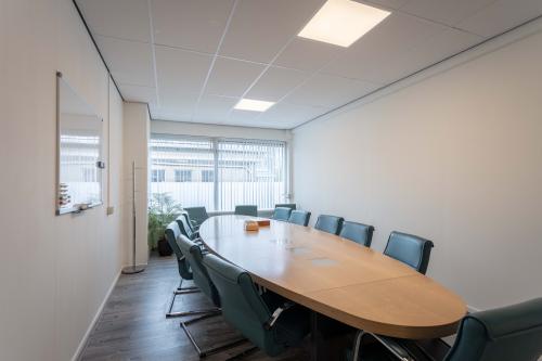 Spacious conference room with an oval table and green chairs at Zeverijnstraat 6, Hilversum, perfect for office space rental.