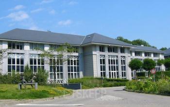Exterior view of office building located at Terhulpsesteenweg 6A, Hoeilaart, featuring large windows and a well-maintained surrounding area, ideal for office space rental.