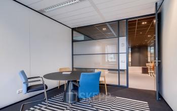 Modern office space at De Wel 20, Hoevelaken, featuring a round table with chairs in a well-lit, functional room ideal for office space rental.