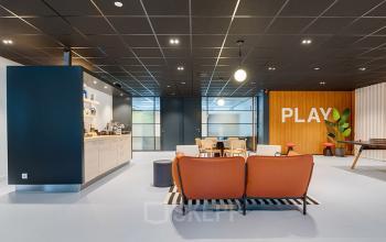 Modern office space rental at De Wel 20, Hoevelaken, featuring a vibrant lounge area with seating, a kitchenette, and a playful ambiance.