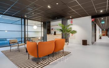 Bright office interior at De Wel 20, Hoevelaken, featuring stylish furniture with orange chairs and a modern design. Ideal for office space rental.