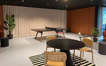 Spacious office interior in Hoevelaken with a ping pong table and seating area, ideal for office space rental.