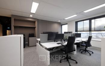 Modern office space with large windows, equipped with desks, chairs, and computer monitors located at Polarisavenue 1, Hoofddorp, available for office space rental.
