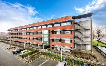 A modern brick office building at Opaallaan 1180, Hoofddorp, showcasing large windows and parking spaces, ideal for office space rental.