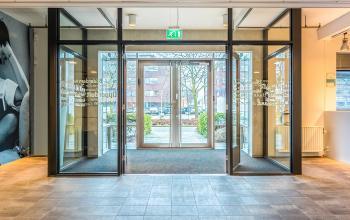 Entrance view of office space rental at Opaallaan 1180, Hoofddorp, showcasing modern glass doors and spacious entry area, ideal for businesses seeking an inviting environment.