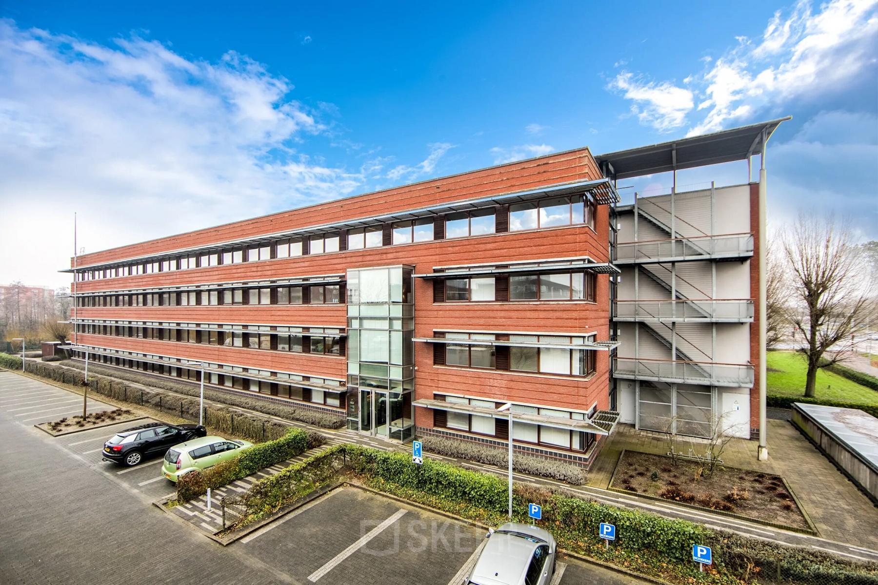 A modern brick office building at Opaallaan 1180, Hoofddorp, showcasing large windows and parking spaces, ideal for office space rental.
