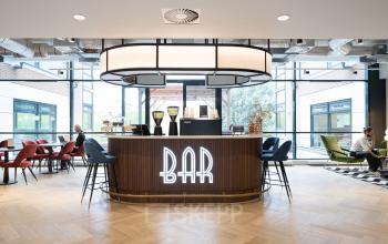 Spacious lounge area at Siriusdreef 60, Hoofddorp, featuring a modern bar with stylish seating and large windows. Ideal for office space rental with relaxed communal vibes.
