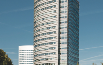 Modern office building at Taurusavenue 1-41, Hoofddorp surrounded by trees and reflecting a clear sky.