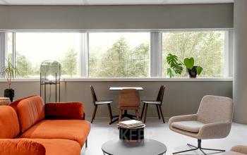 Bright, furnished office space at Taurusavenue 1-41 in Hoofddorp, featuring a cozy seating area with orange and grey chairs and a small round table, ideal for office space rental.