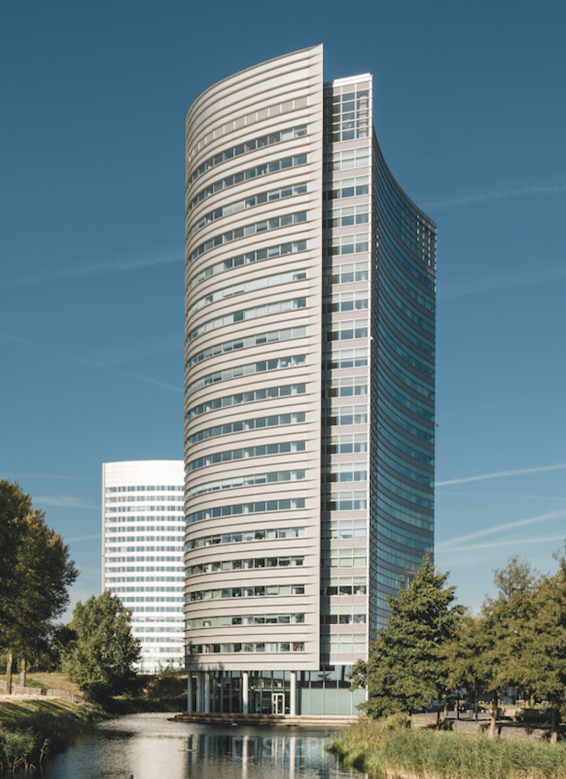 Modern office building at Taurusavenue 1-41, Hoofddorp surrounded by trees and reflecting a clear sky.