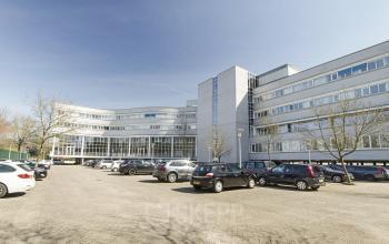Exterior view of a modern office building located at Planetenweg 5, Hoofddorp, showcasing ample parking space and a sleek facade, ideal for office space rental.