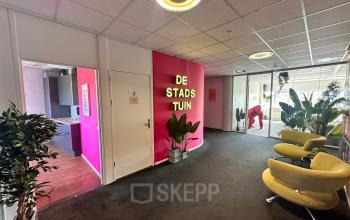 Bright reception area at Planetenweg 5, Hoofddorp with colorful wall art, potted plants, and cozy seating. Ideal choice for office space rental, offering a welcoming ambiance for professionals.