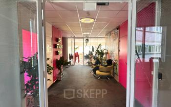 Vibrant office entrance at Planetenweg 5, Hoofddorp, with colorful walls, plants, and seating areas. Ideal setting for office space rental.