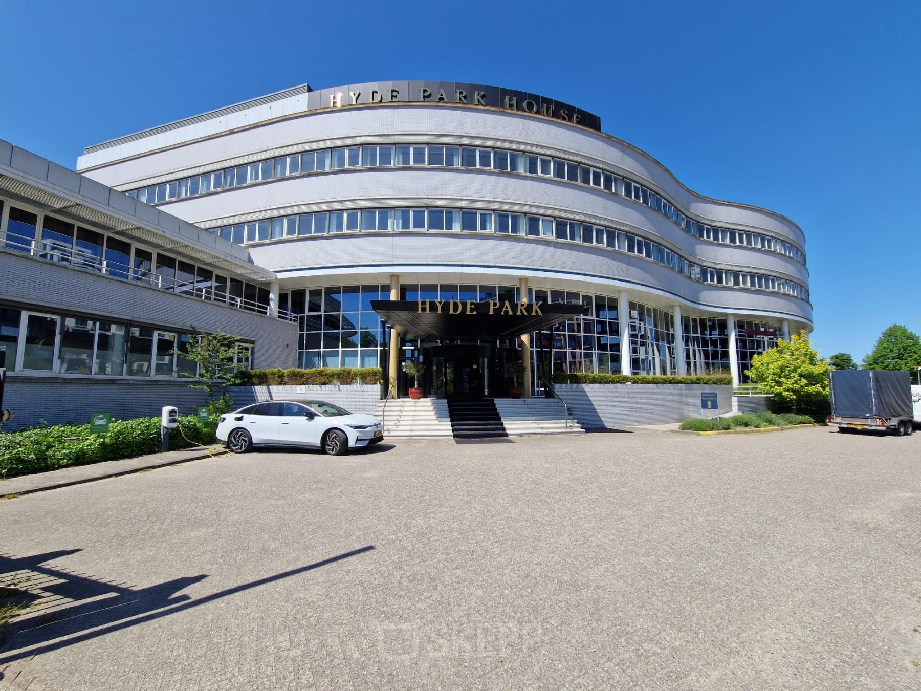 Exterior view of the office building at Planetenweg 5, Hoofddorp, showcasing modern architecture with a curved facade, large windows, and entrance steps. Ideal for businesses seeking office space rental in a strategic location.
