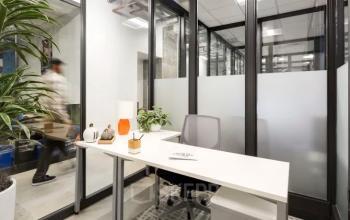 Modern office space at Siriusdreef 17, Hoofddorp with sleek furnishings and glass partitions, ideal for rent office space enthusiasts. A person is walking past, adding a dynamic touch to the office environment.