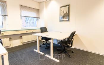 A well-lit private office space rental at Siriusdreef 17, Hoofddorp featuring a contemporary desk, chairs, and framed artwork on the wall.