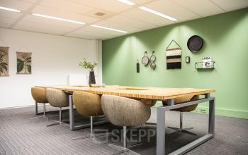 Modern office to rent at Meidoornkade 22, Houten, featuring a stylish meeting area with a wooden table and comfortable chairs, suitable for office space rental.