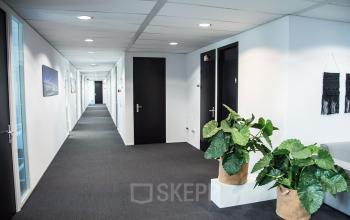 Bright hallway at Meidoornkade 22 in Houten, showcasing an inviting office space rental with modern decor and potted plants.