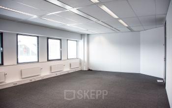 Empty office space with large windows, carpeted floor, and overhead lighting at Meidoornkade 22, Houten, available for rent.