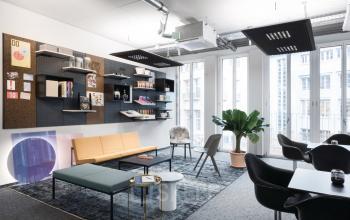 Modernes möbliertes Büro in Christophstraße 15-17, Köln Innenstadt, mit Regalen, Pflanze und verschiedenen Stühlen. Verschiedene Büroaccessoires an der Wand.