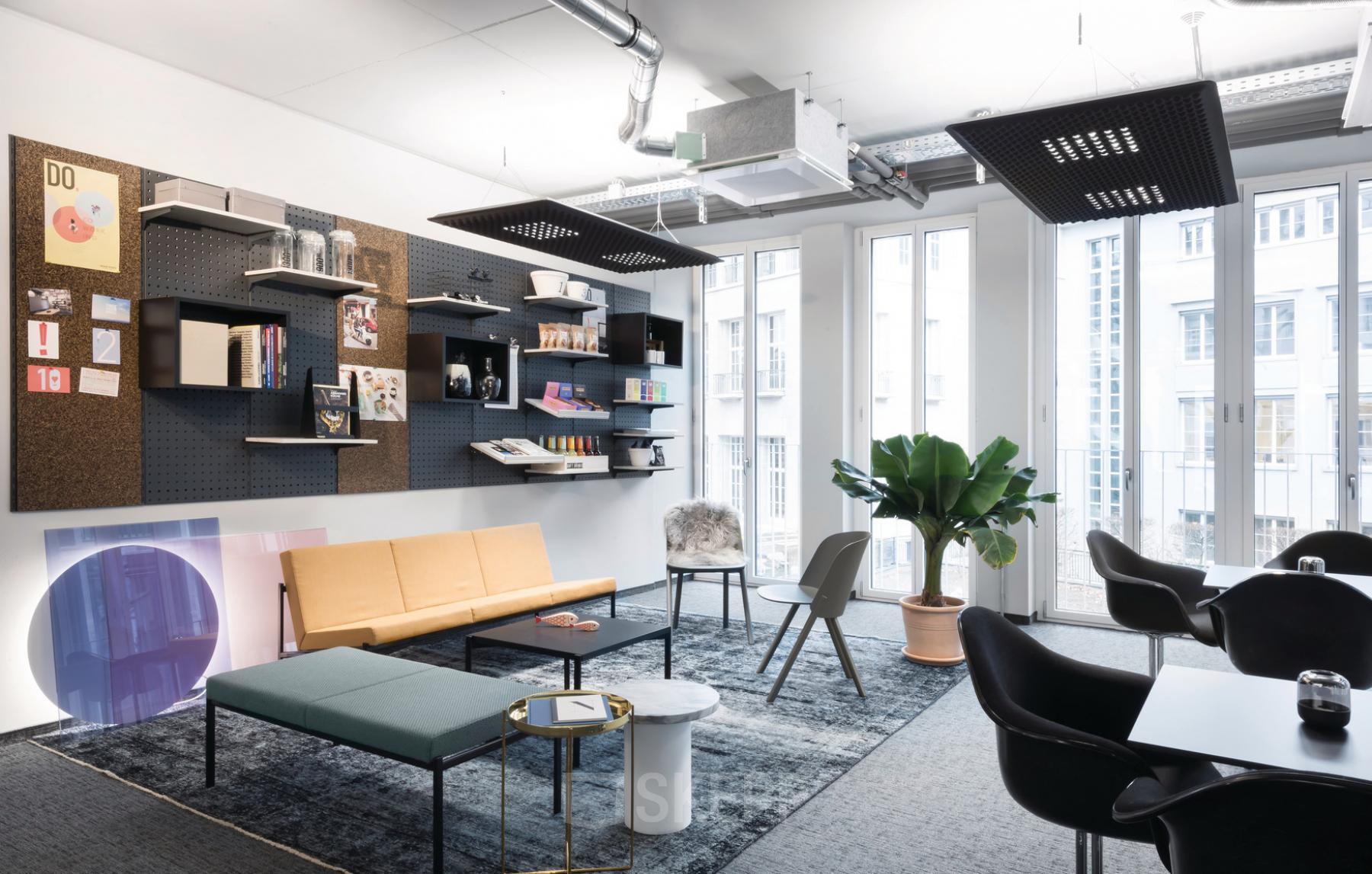 Modern office space at Christophstraße 15-17, Cologne Center, furnished with contemporary seating, decorative wall shelves, and vibrant natural light through large windows.