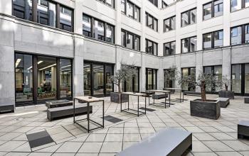 Modern courtyard of office building at Tunisstraße 19-23, Cologne Center, Cologne, featuring potted trees and benches.