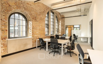 Moderner büroraum mieten in Klagenfurt, St. Ruprechter Str. 90 mit großen Fenstern und industriellem Charme, ausgestattet mit mehreren Tischen und Bürostühlen.