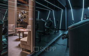 Modern furnished office space rental at Oudhuizerstraat 31, Klarenbeek featuring comfortable seating and high-tech equipment in a sleek, contemporary design with dim lighting and reflective mirrors.