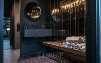 Modern office space at Oudhuizerstraat 31, Klarenbeek with sleek interior design featuring dark tiles, a large mirror, and contemporary fixtures.