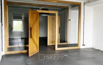 Wnętrze biura na wynajem na Przemysłowej 12 w Krakowie, przestronne z dużymi drewnianymi drzwiami i jasną podłogą.