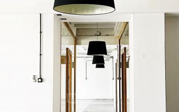 Eleganckie, przestronne powierzchnie biurowe na wynajem w Krakowie przy ulicy Przemysłowej 12, oświetlone dużymi, designerskimi lampami