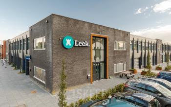 Exterior view of an office building at Industriepark 5B, Leek, featuring a modern facade and prominent signage. Ideal for office space rental, the location offers convenient parking.