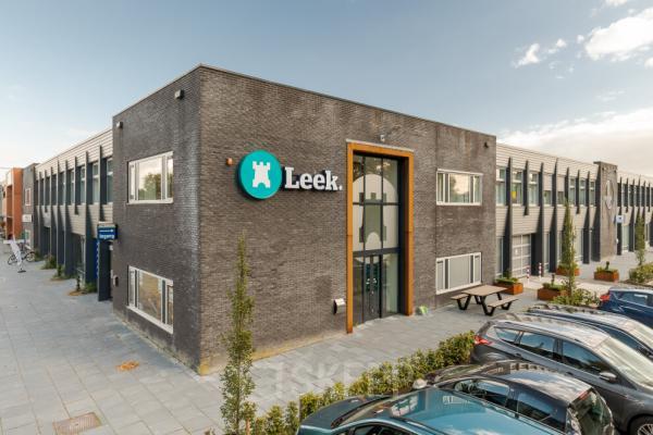 Exterior view of an office building at Industriepark 5B, Leek, featuring a modern facade and prominent signage. Ideal for office space rental, the location offers convenient parking.