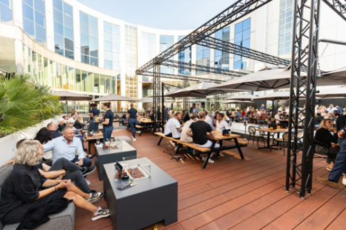 Outdoor terrace at Lange Marktstraat 1 in Leeuwarden, bustling with people enjoying casual conversations and networking, ideal for informal business gatherings. Perfect for those seeking vibrant office space rental.